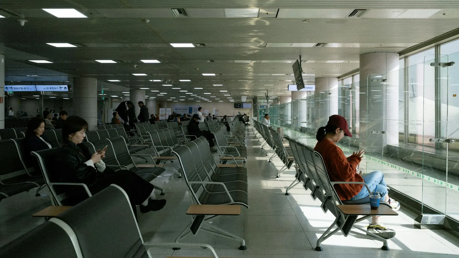 Travellers looking at their phones in a quiet airport departure lounge