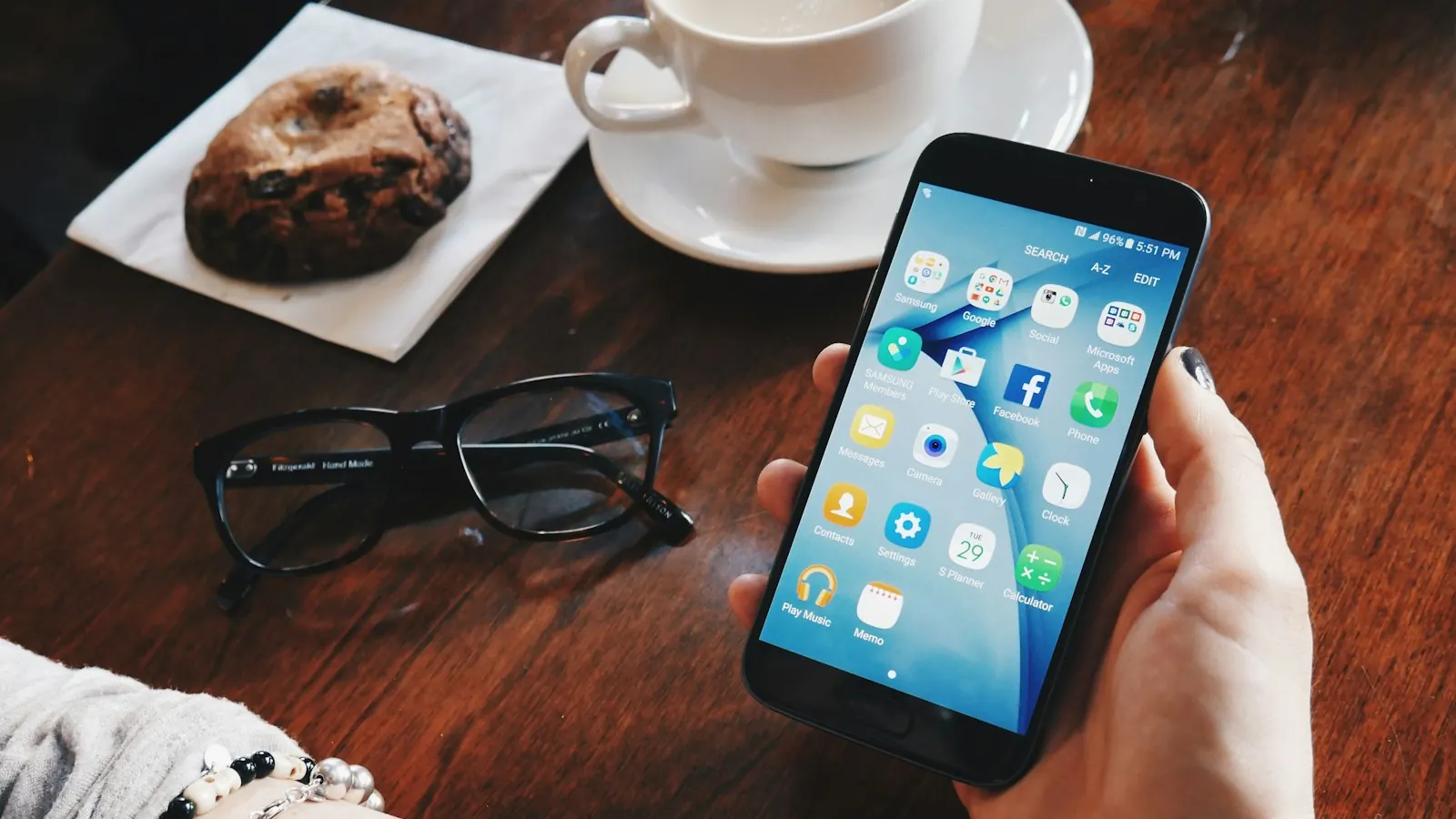 An Android phone held over a café table next to a coffee cup