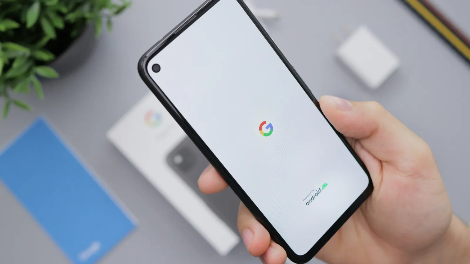 Una mano sujeta un móvil Android con el logotipo de Google en la pantalla sobre un escritorio